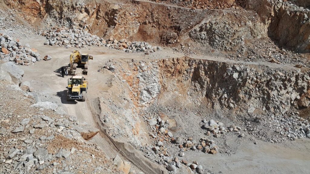 An open-pit mining site featuring excavators and loaders amid rocky terrain.