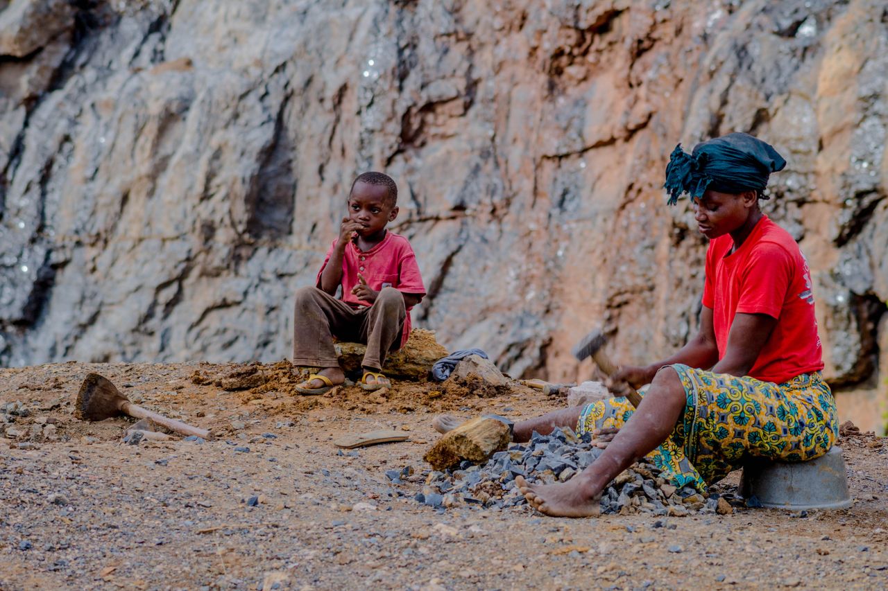 A mother and child in a rural setting mining stones together.